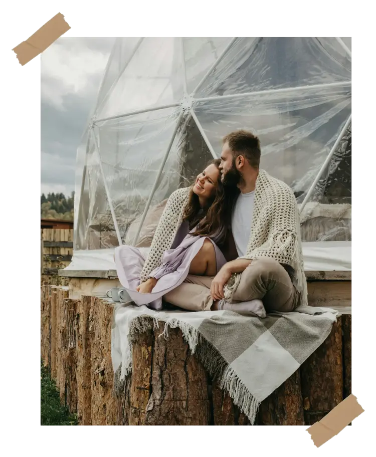 A couple wrapped in blankets sharing a cozy moment outdoors, symbolizing the warmth and nostalgia of creating a personalized couples book to cherish memories.