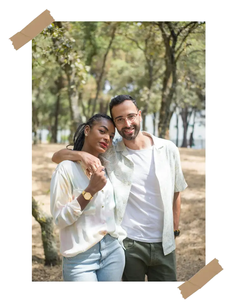 A smiling couple walking in the park, sharing a warm and affectionate moment together.