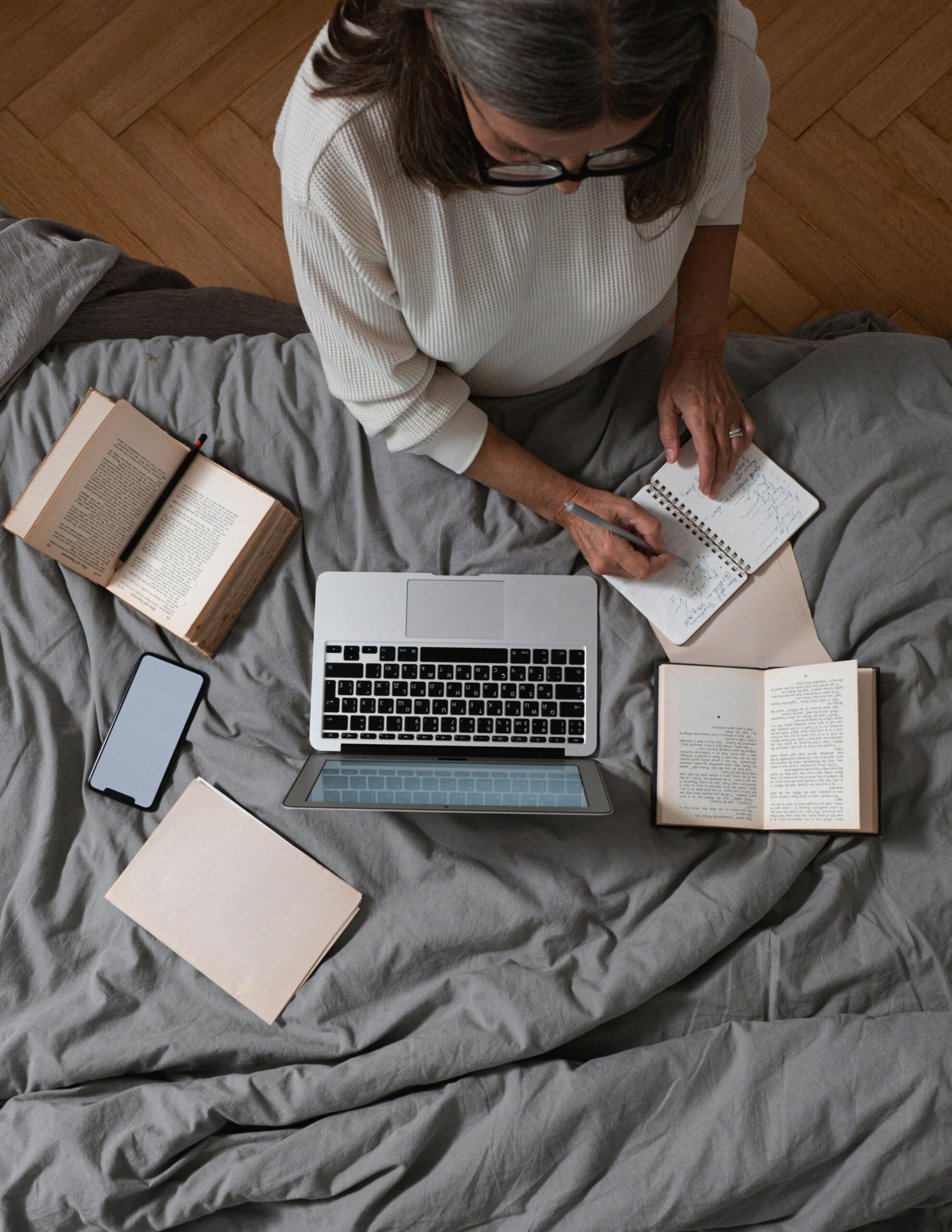 A senior woman writing notes about her autobiography on the bed